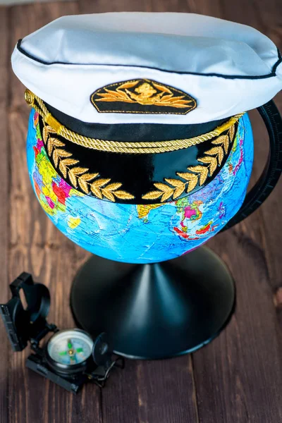 Mütze des Schiffskapitäns auf dem Globus, daneben liegt ein Compas — Stockfoto