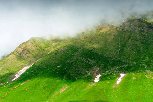 Pendiente de montaña cubierta de hierba con restos de nieve después de wi — Foto de Stock