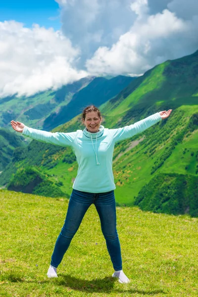 Женщина в горах с распростертыми к бокам руками с радостью — стоковое фото