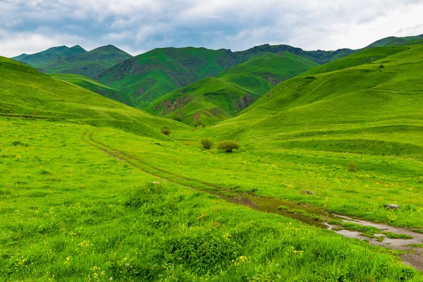 Grønne bjerge i Armenien i forsommeren, grusvej - Stock-foto