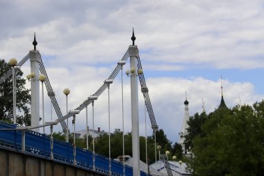 Yaroslavl'daki Kotorosl nehri üzerinde kablolu köprü kaldı. Damansky adasından manzara. Güzel yaz günü; su yüzeyinde sahil ve köprü yansıması. Şehirde Kurtarıcı Kilisesi