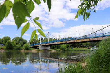 Yaroslavl'daki Kotorosl nehri üzerinde kablolu köprü kaldı. Damansky adasından manzara. Güzel yaz günü; su yüzeyinde sahil ve köprü yansıması