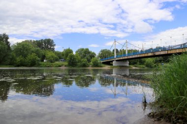 Yaroslavl'daki Kotorosl nehri üzerinde kablolu köprü kaldı. Damansky adasından manzara. Güzel yaz günü; su yüzeyinde kıyı ve köprü yansıması