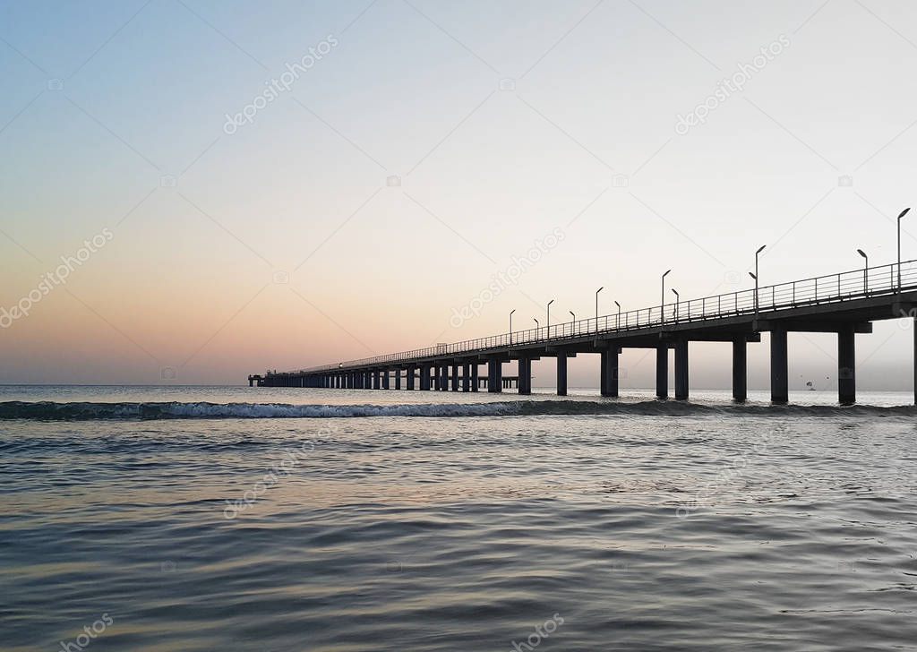 Sea pier at sunset. Anapa, Dzhemete. Beautiful sunset sky gradient. Effect of transfer a color image to black and white