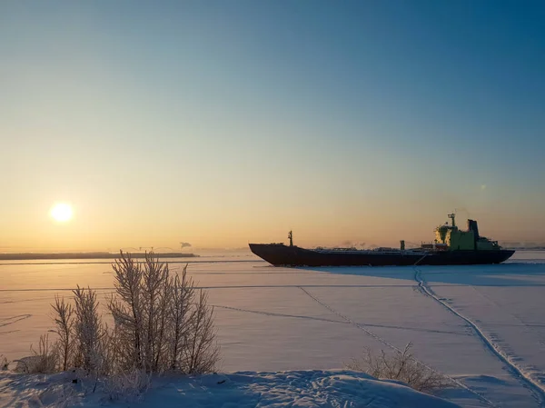 Arkhangelsk. Sunny winter day on the Bank of the Northern Dvina. January. Merchant ship in the ice on the fairway of the port of Arkhangelsk. — Stock Image Arkhangelsk Sunny Winter Day Bank Northern Dvina January Merchant Ship Stock Picture