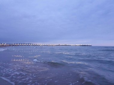 Karadeniz kıyısında sıcak bir yaz gecesi. Anapa, Krasnodar bölgesi. Deniz dalgası, gece. Rıhtımdaki ışıklar