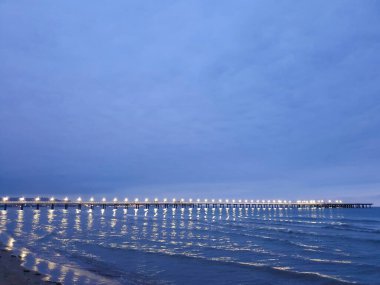 Karadeniz kıyısında sıcak bir yaz gecesi. Anapa, Krasnodar bölgesi. Deniz dalgası, gece. Rıhtımdaki ışıklar