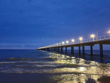 Karadeniz kıyısında sıcak bir yaz gecesi. Anapa, Krasnodar bölgesi. Deniz dalgası, gece. Rıhtımdaki ışıklar