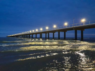 Karadeniz kıyısında sıcak bir yaz gecesi. Anapa, Krasnodar bölgesi. Deniz dalgası, gece. Rıhtımdaki ışıklar