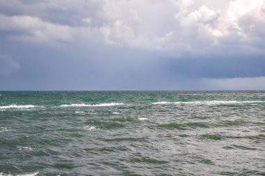 Karadeniz kıyısında. Sörf. Hafif meltem. Küçük dalgalar, beyaz köpük, su ile. Gri, siyah, mavi ve yeşil rengi. Kasvetli gökyüzü, yağmur bulutları. Ufuk çizgisi olağanüstü güzel.