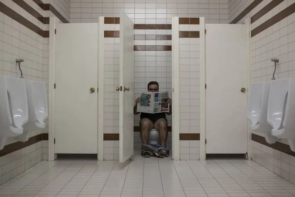 Человек Читает Газету Общественном Туалете Смотрит Камеру — стоковое фото