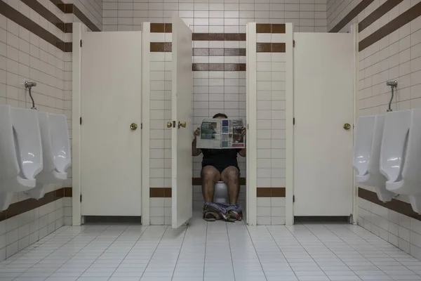 Человек Читающий Газету Общественном Туалете — стоковое фото