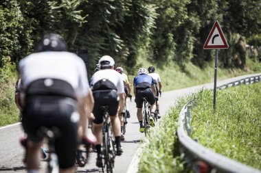 güneşli bir günde sırtında bir yoldan dizilmiş bisikletçiler Grup