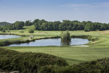 Panoramik göl ve güneşli bir sonraki delik için yolda oyuncular ile bir golf sahasının