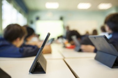öğretmenle dinlerken çocuk kendi tablet ile sınıf içinde kendi sınıf arkadaşlarıyla çalışma