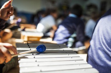 Eller ksilofon müzik dersinde oynarken sopaları ile kızın