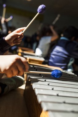 Eller ksilofon müzik dersinde oynarken sopaları ile kızın