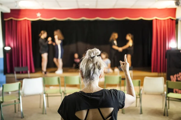 girls praising a theater class before the look of her blonde teacher on her back