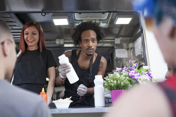 young woman and redhead working on a food truck with an afro man