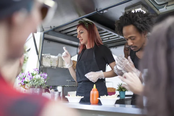 young woman and redhead working on a food truck with an afro man