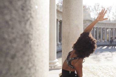 Pratik yoga sütunlar arasında açık havada güzel afro kadın