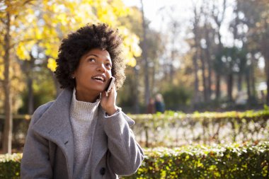 Eğleniyor güzel afro kadın parkta onun akıllı telefon ile iletişim