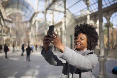 Eğleniyor güzel afro kadın parkta onun akıllı telefon ile iletişim