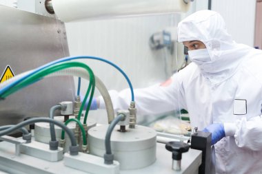 Hijyenik iş elbiselerine sahip bir işçi et kesme odasının koruyucu atmosfer paketleme makinesini kullanıyor.