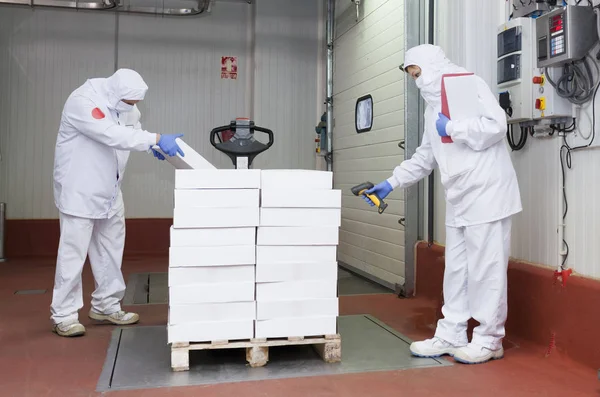 Meat cutting room workers weighing a pallet of boxes at the loading dock