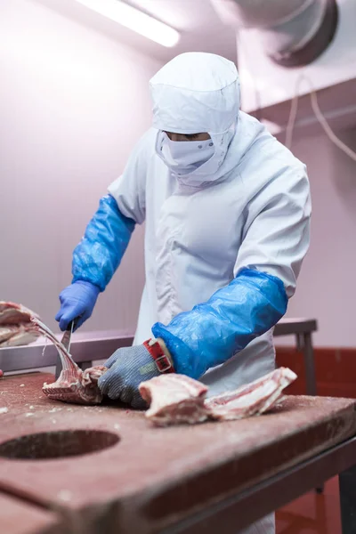 Meat cutting room worker preparing a rack of lamb