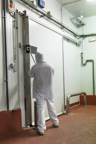 meat cutting room worker manipulating a sliding door of the refrigerator chamber