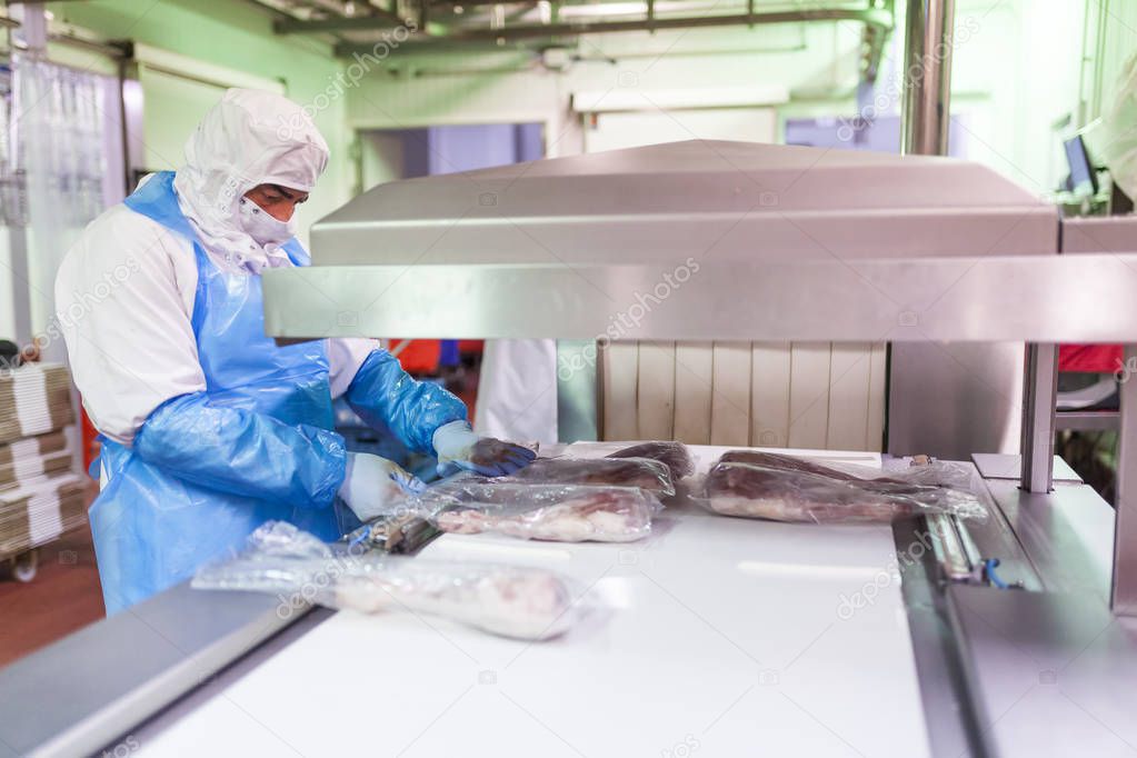 worker with hygienic clothing using the vacuum packaging machine of the meat cutting room