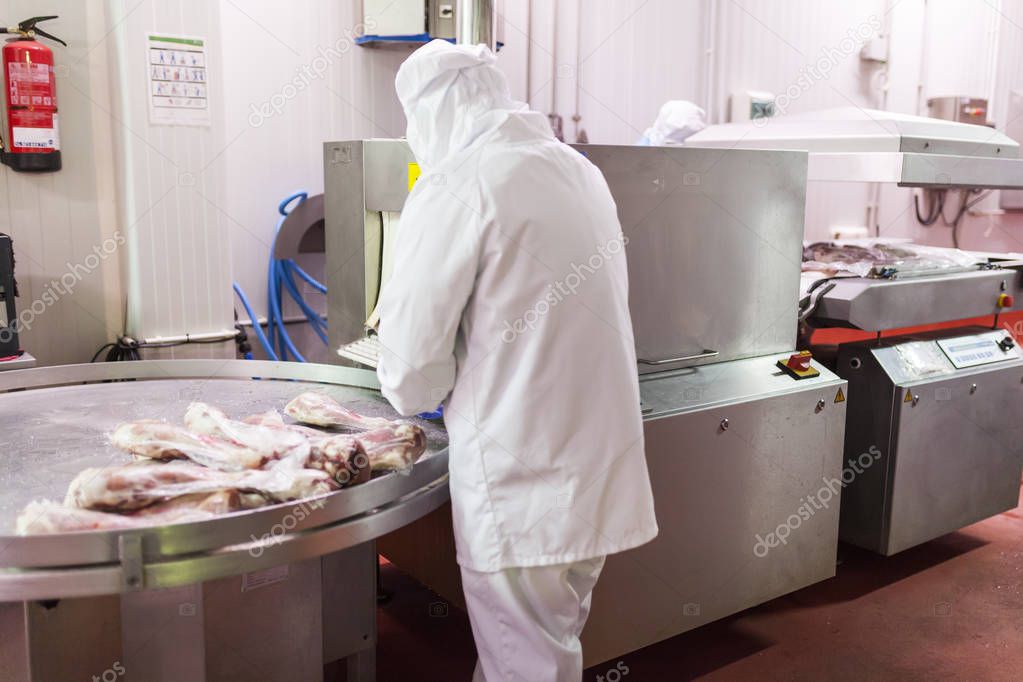 worker with hygienic clothing using the vacuum packaging machine of the meat cutting room