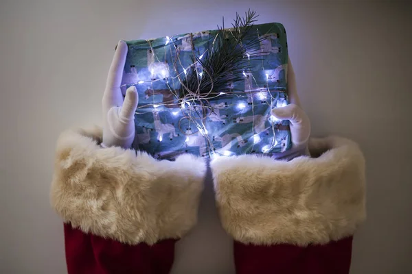 Brazos de Santa Claus sosteniendo un regalo —  Fotos de Stock