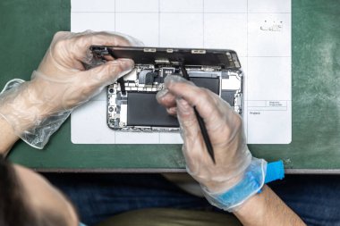 Tanımlanamayan teknisyen tamirhanesinde akıllı telefonu tamir ediyor.