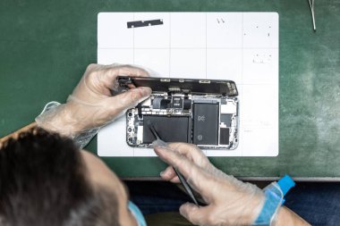 unrecognizable technician repairing smart phone in his repair shop clipart