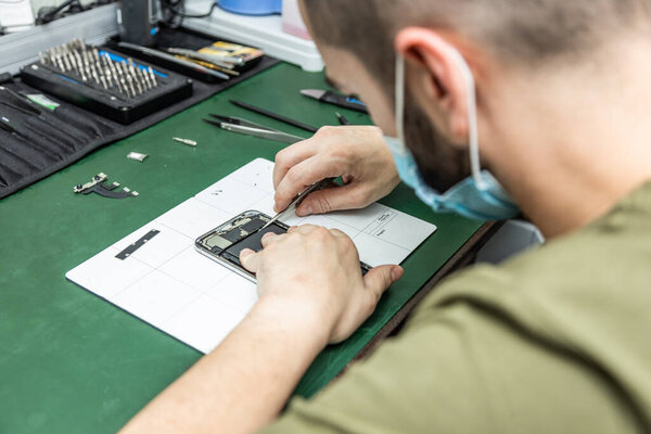 unrecognizable technician repairing smart phone in his repair shop