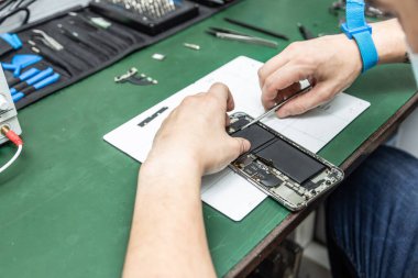 Tanımlanamayan teknisyen tamirhanesinde akıllı telefonu tamir ediyor.