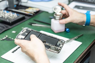 Tanımlanamayan teknisyen tamirhanesinde akıllı telefonu tamir ediyor.