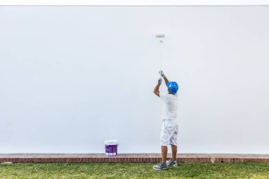 Tanımlanamayan genç bir ressam bir apartman cephesini boyuyor.