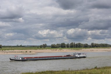 Beneden Leeuwen, Hollanda-31 Ağustos 2018: Nehrin Waal Beneden Leeuwen, Hollanda yakınındaki floodplains yukarıda karanlık rainclouds ile teknede.