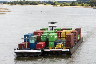 Beneden Leeuwen, Hollanda-31 Ağustos 2018: konteyner gemisi Beneden Leeuwen, Hollanda yakınındaki floodplains yukarıda karanlık rainclouds ile Waal Nehri üzerinde.