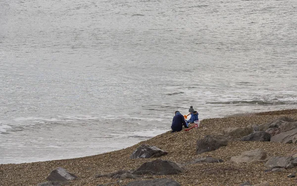 バートン海 イングランド 2018 秋の防寒服を着た女性と座って遊ぶビーチで子供 — ストック写真