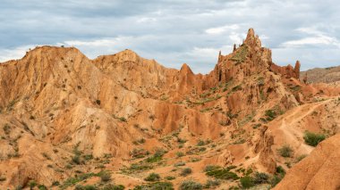 Kırgızistan 'daki Issyk kul Gölü' ndeki peri masalı kanyonu. Kızıl dağlar ve kara yağmurlu gökyüzü..