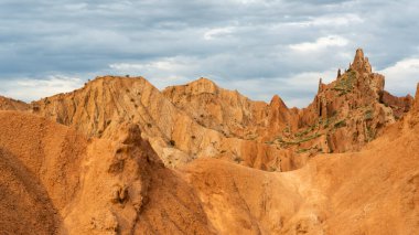 Kırgızistan 'daki Issyk kul Gölü' ndeki peri masalı kanyonu. Kızıl dağlar ve kara yağmurlu gökyüzü..