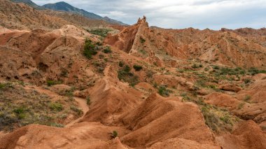 Kırgızistan 'daki Issyk kul Gölü' ndeki Peri Masalı Kanyonu manzarası. Kızıl dağlar ve koyu yağmurlu gökyüzü..