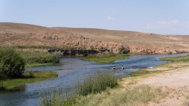 Kurty, Kazakistan - 22 Temmuz 2019: Kurty yakınlarındaki Kurty Nehri 'nde yüzen iki kişi yaz günü bozkır satın aldı.