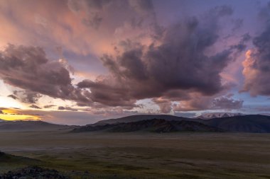 Gün batımında koyu renkli bulutlar ve dağlarla Moğolistan 'ın Steppe' i.
