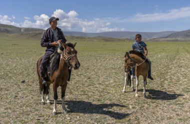 Tolbo, Moğolistan - 4 Ağustos 2019: Çocuk ve adam Moğolistan bozkırında at sırtında.