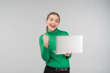 Hevesli genç kadın laptop ile muzaffer ifade arıyor. Aygıt ve yumruk kadar tutar. -Konsept görüntü